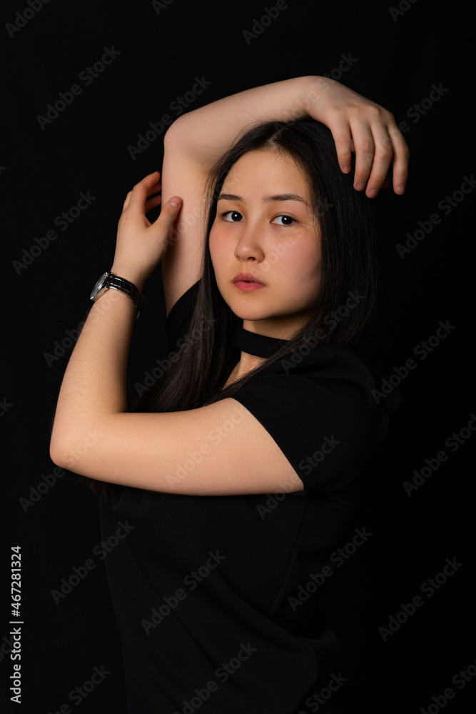 portrait of a girl in black clothes with long black hair on a black background. Oriental beauty portrait of a girl in black clothes with long black hair on a black background. Oriental beauty