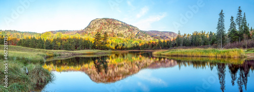 Just after sunrise, the Beehive, a summit on Mt. Desert Island, Maine, is surrounded with fall foliage color and displays a reflection on Beehive Lagoon near Sand Beach in Acadia National Park.