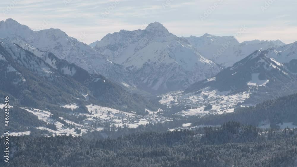 Aerial view overlooking a town, under snowy mountains, in Germany - tracking shot Aerial view overlooking a town, under snowy mountains, in Germany - tracking shot