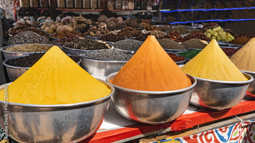 Seasonings for various dishes are sold on the market in Egypt. In the foreground - bright orange and yellow spices are lined with slides in metal bowls.