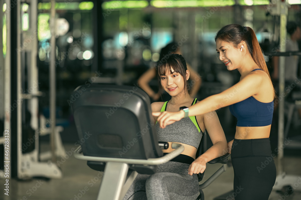 Fototapeta premium Two beautiful fitness woman working out in gym together.