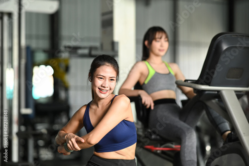 Smiling fitness woman in sportswear doing stretching exercises before workout at gym