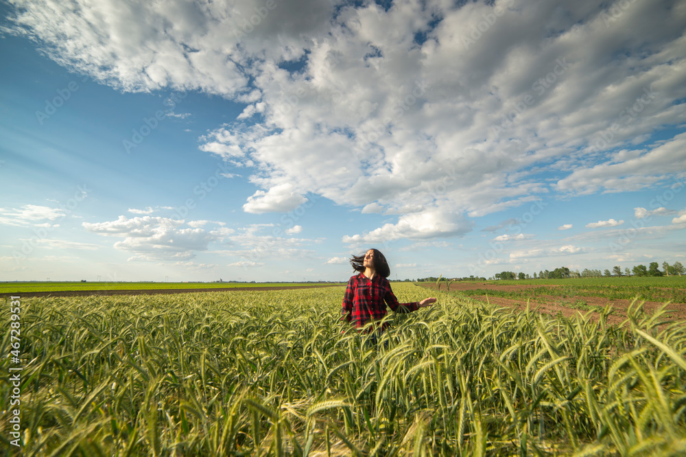 A young woman in a green wheat field