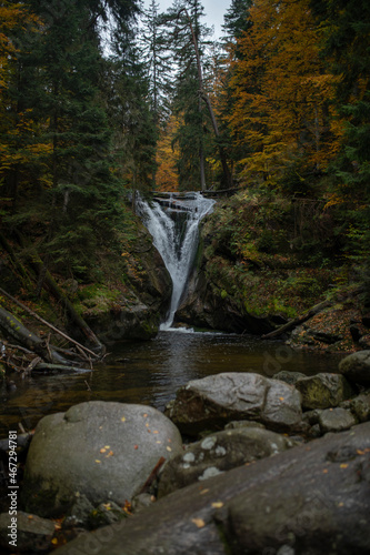 Beautiful waterfall with trees, red leaves, rocks and stones in the autumn forest. Szklarka Waterfall 