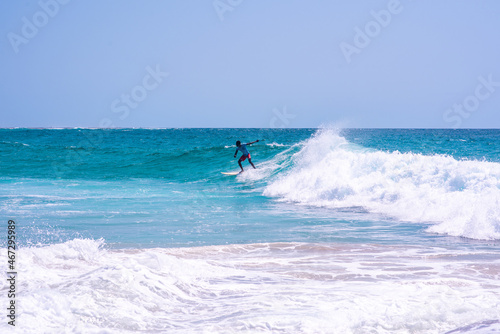 Young man seen riding wave with his surfboard