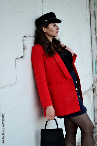 A young long-haired brown-haired woman in a black beret and a red coat on the station platform