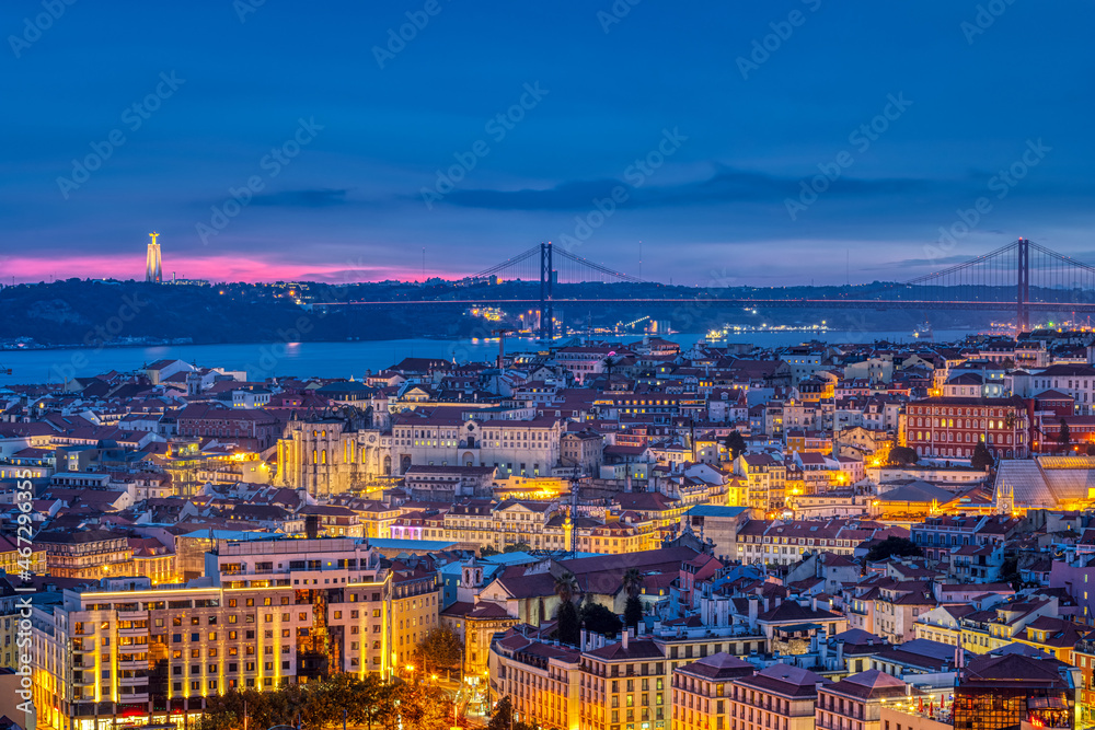 The lights of Lisbon in Portugal with the Sanctuary of Christ the King and the 25 de Abril Bridge