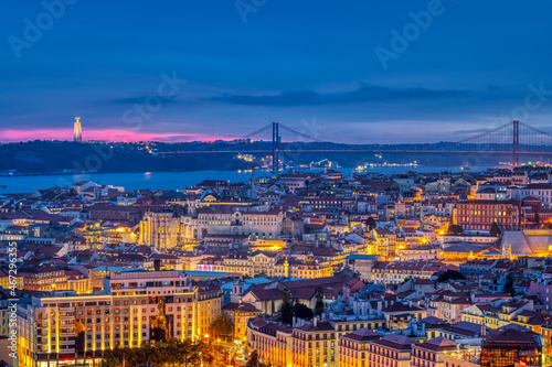 The lights of Lisbon in Portugal with the Sanctuary of Christ the King and the 25 de Abril Bridge