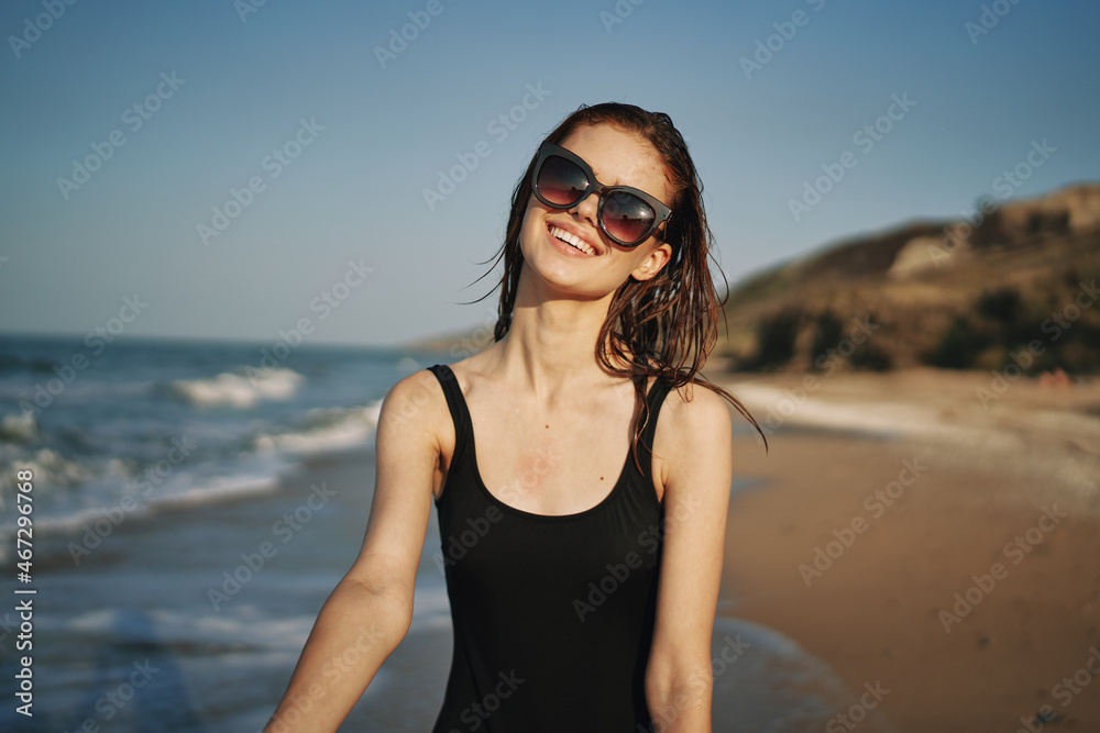 cheerful woman in a black swimsuit walking along the beach tropics summer cheerful woman in a black swimsuit walking along the beach tropics summer