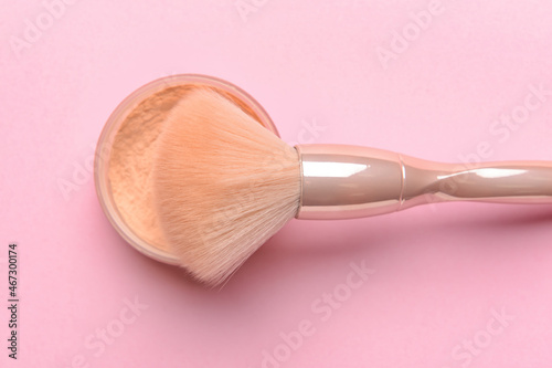 Professional makeup brush with face powder on color background