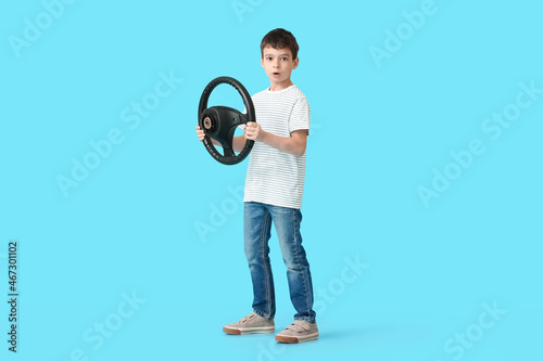 Shocked little boy with steering wheel on color background © Pixel-Shot