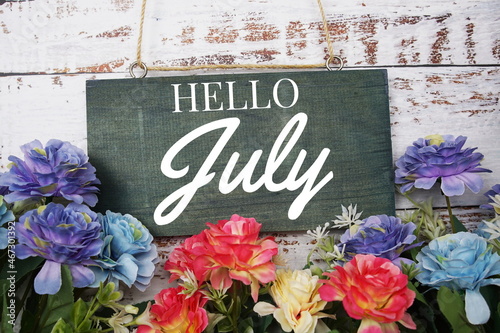 Hello July typography text decorate with flower on wooden background © may1985