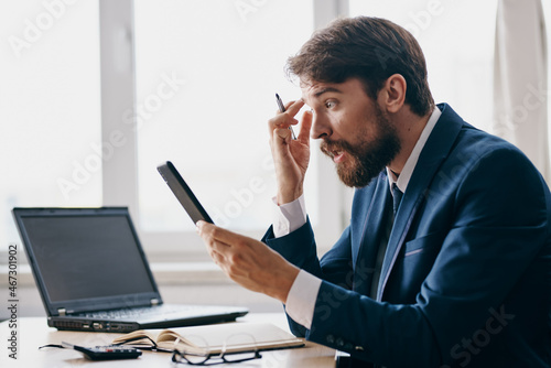 bearded man sitting at a desk in front of a laptop stress anger