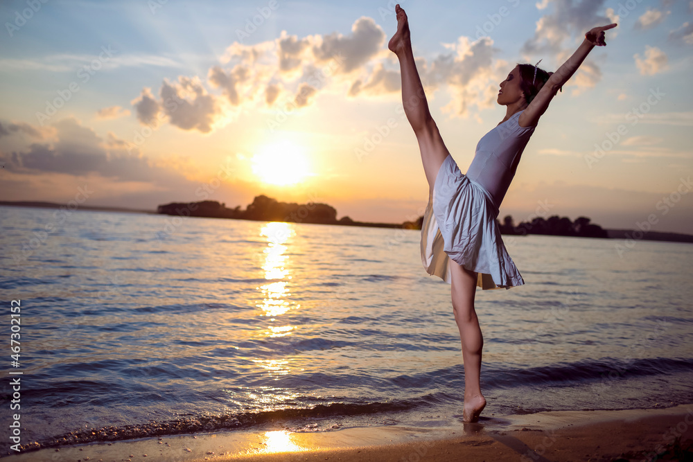 Passion and Love for Dance With Japanese Ballet Dancer in White Dress And Silver Crown Standing In Ocean Waves And Showing Ballet Pas With Lifted Hands Against Picturesque Sunset At Sea.