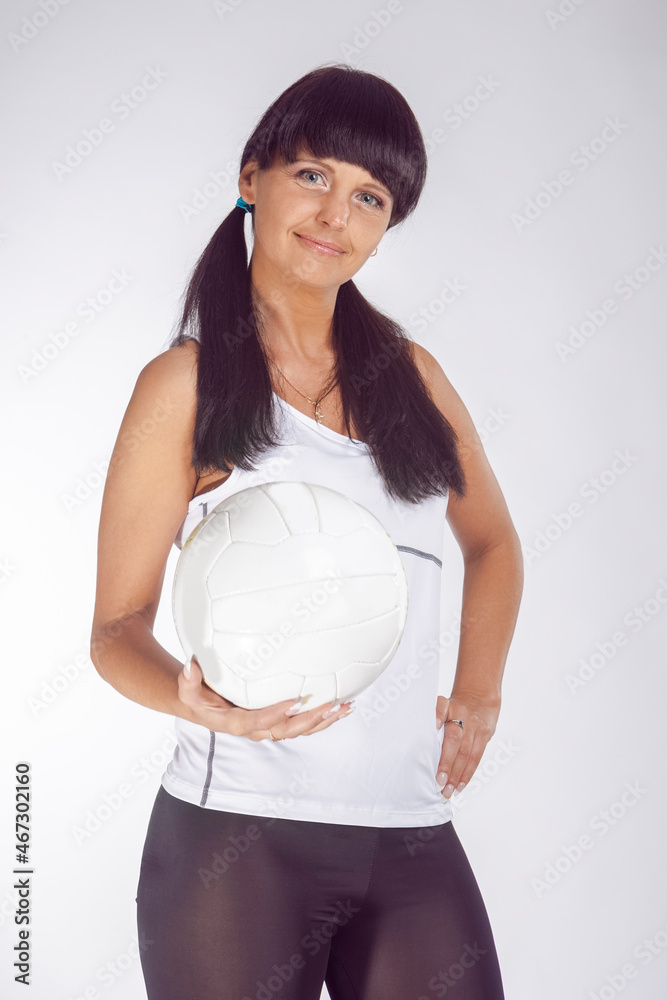 Sport Ideas and Concepts. Portrait of Smiling Caucasian Female Volleyball Athlete During Training Against White Background While Holding a Ball In Hands. Sport Ideas and Concepts. Portrait of Smiling Caucasian Female Volleyball Athlete During Training Against White Background While Holding a Ball In Hands.