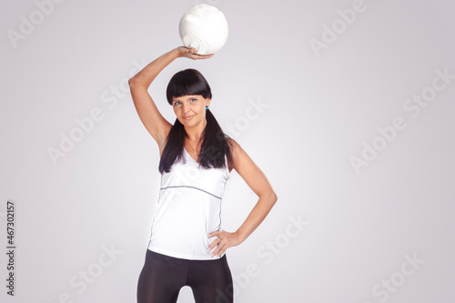 Game Sport Ideas.Positive Caucasian Female Volleyball Athlete in Training Outfit Posing Against White While Holding a White Ball photo