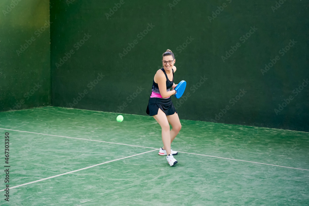 Sportswoman hitting padel ball with racket
