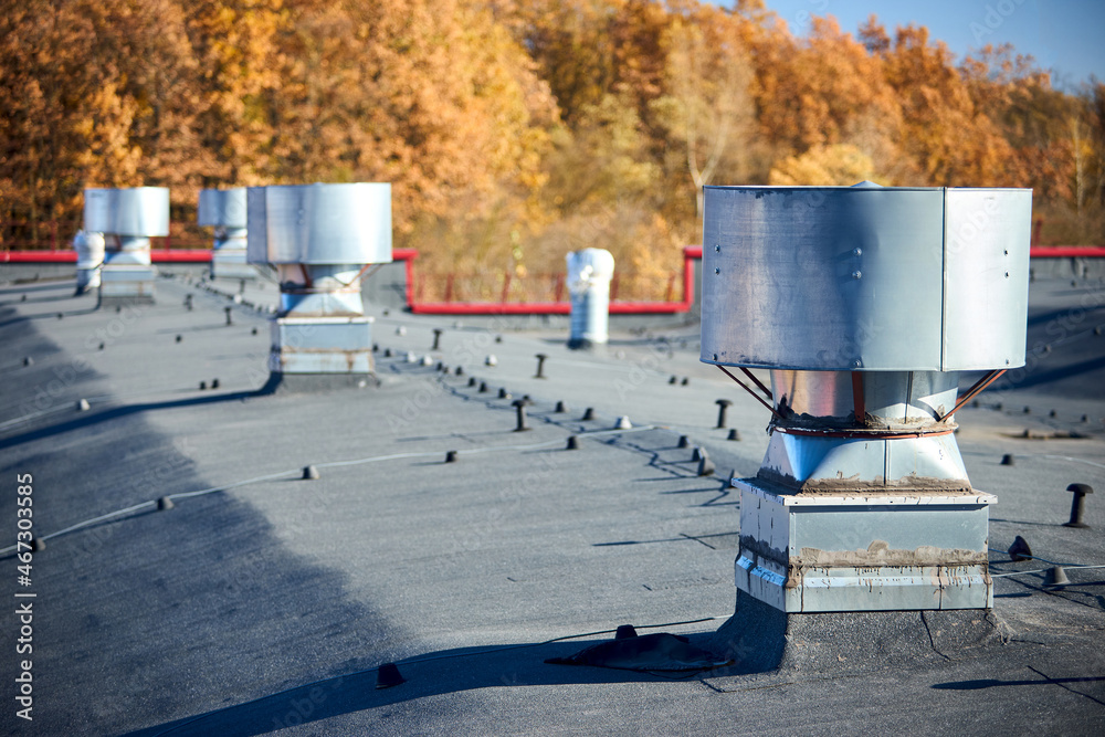 Air roof exhaust ventilation fan system of industrial large commercial  building with hooded chimneys flues and ducts in row on roof top selective  focus with lightning protection system. Stock Photo | Adobe