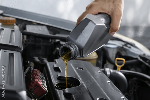 Male mechanic pouring motor oil from canister into car engine