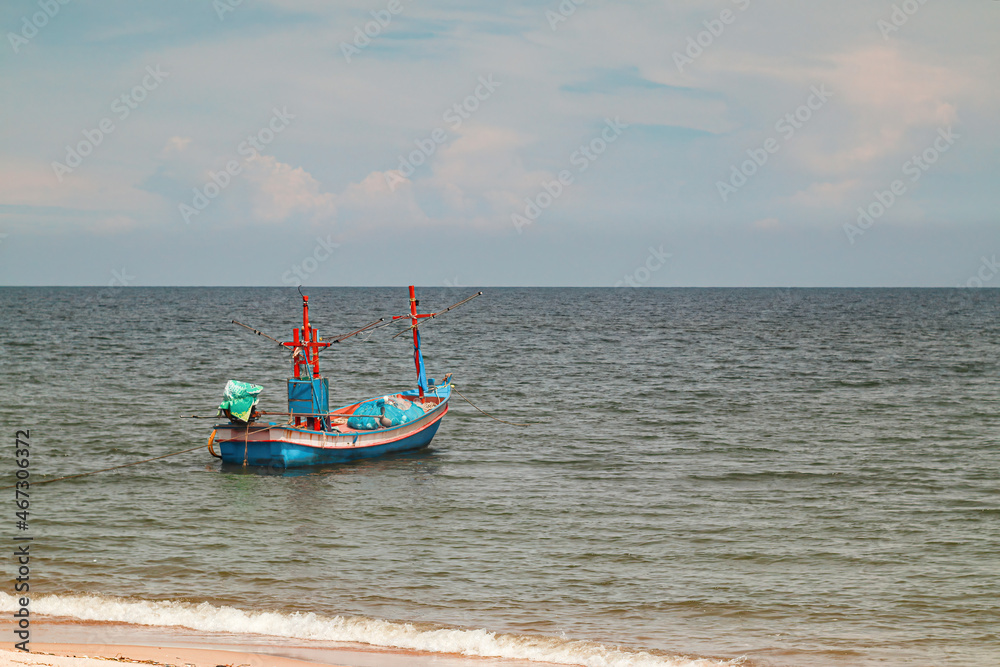 Fisherman boat float in the sea ocean near sand beach shore with hazy blue sky background landscape