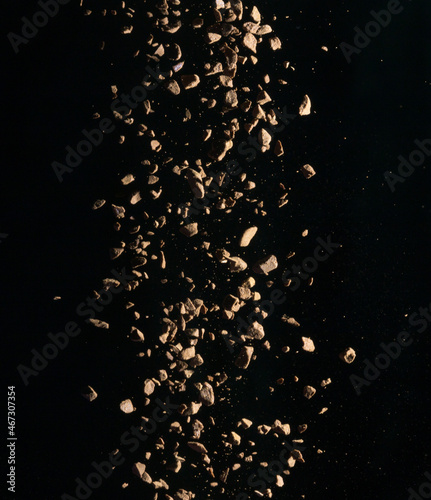 Flying coffee beans isolated on black background. Roasted coffee beans against a flash of light