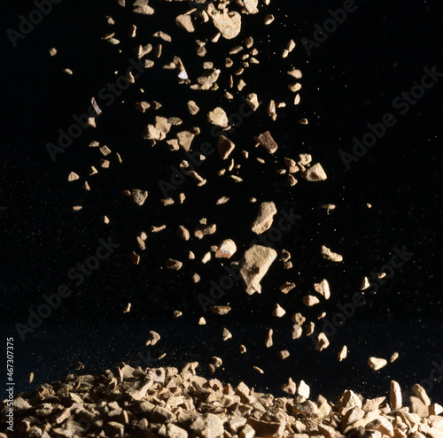 Flying coffee beans isolated on black background. Roasted coffee beans against a flash of light