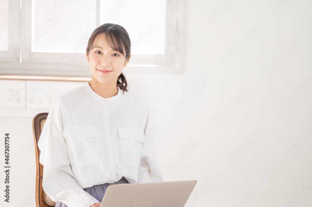 パソコンの仕事をするカメラ目線の美しいアジア人女性　右にコピースペースあり　