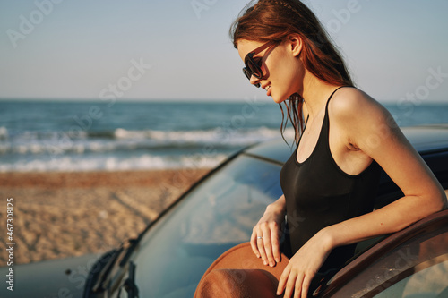 woman on the beach is with a car wearing sunglasses travel © VICHIZH