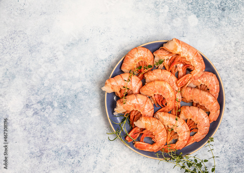 Raw red Argentine shrimps on ceramic plate, blue concrete background. Ocean jumbo shrimps. Top view.