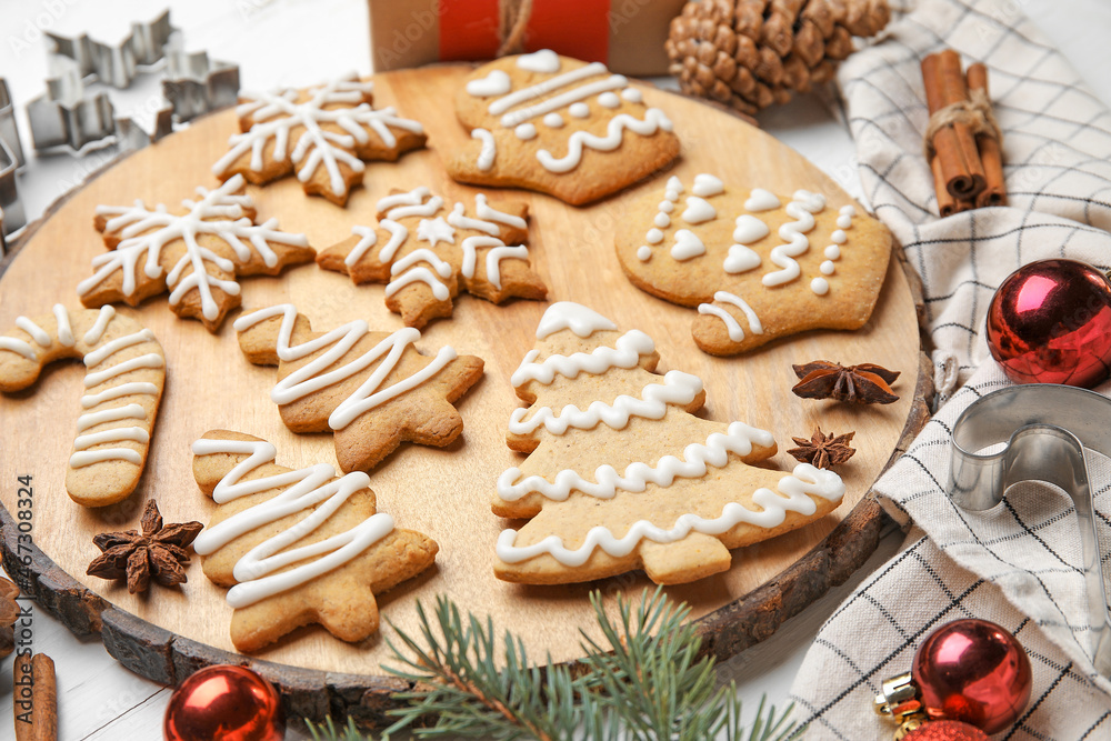 Board with Christmas gingerbread cookies on white wooden background
