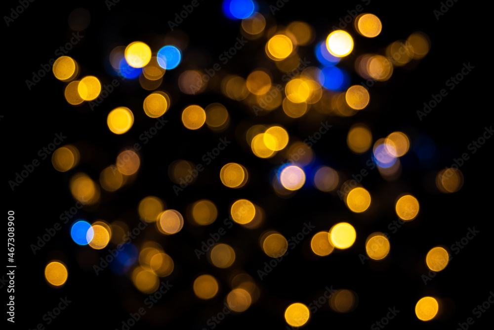 Perfect bokeh for a festive New Year and Christmas background. Defocused abstract yellow and blue light circles. Bokeh is distributed throughout the frame