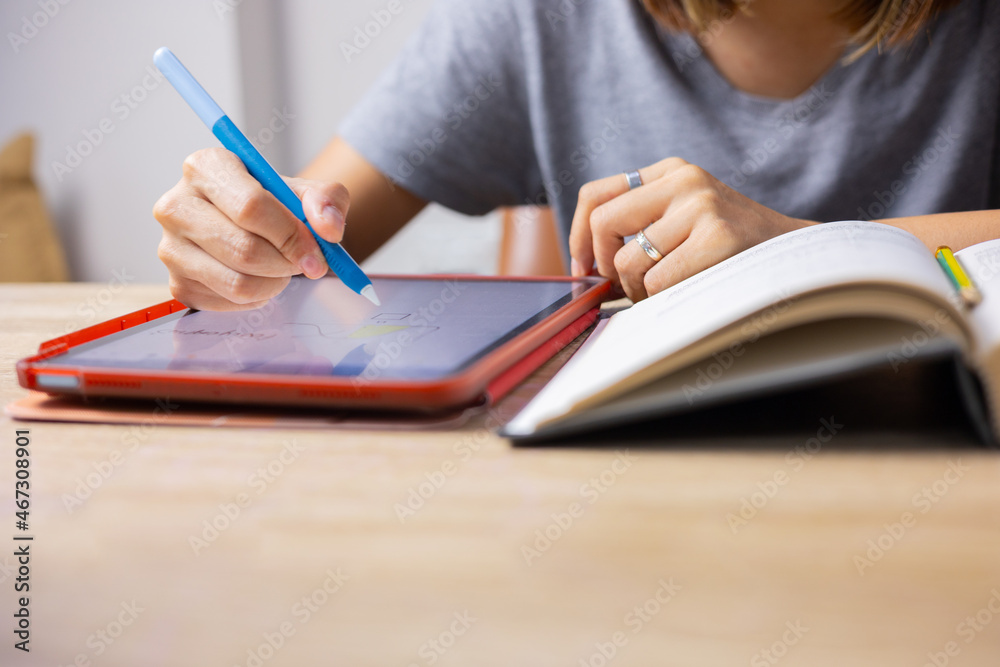 Close up and selective focus shot of woman hands who is writing on tablet screen by using stylus pen at home shows education concept of hard studying by using digital and online technology. Close up and selective focus shot of woman hands who is writing on tablet screen by using stylus pen at home shows education concept of hard studying by using digital and online technology.