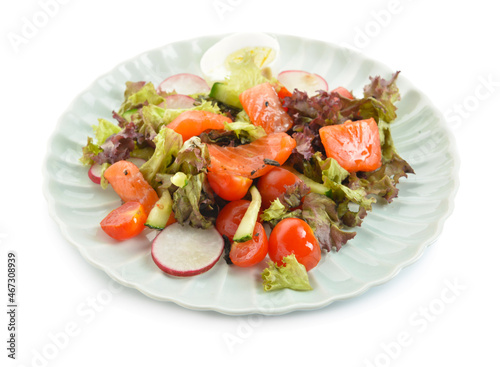 Tasty salad with salmon, egg and fresh vegetables in plate on white background