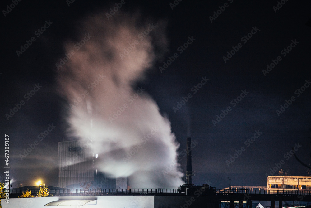 Night landscape with a view of smoking chimneys in the factory lights