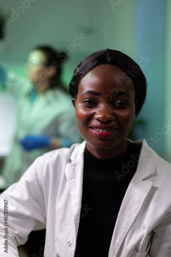 Portrait of african american microbiologist doctor looking into camera working in microbiology hospital laboratory. Medical team analyzing genetically modified plant during agriculture experiment