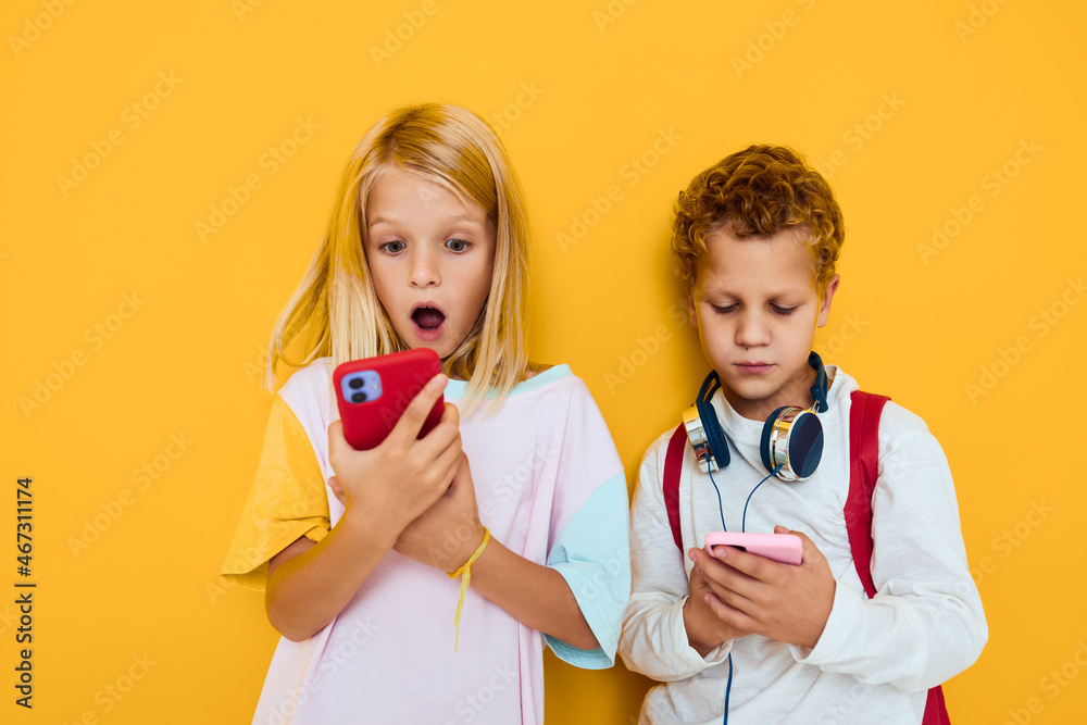 school children use gadgets with headphones yellow background school children use gadgets with headphones yellow background