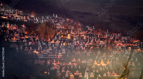 Candle lights on graves in cemetery at night on All Saints’ Day or All Souls’ Day or Halloween