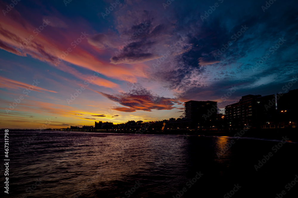 Atardecer con cielo espectacular. Paseo marítimo. Costa urbana. Playa de la ciudad con cielo bonito. Atardecer crepuscular.