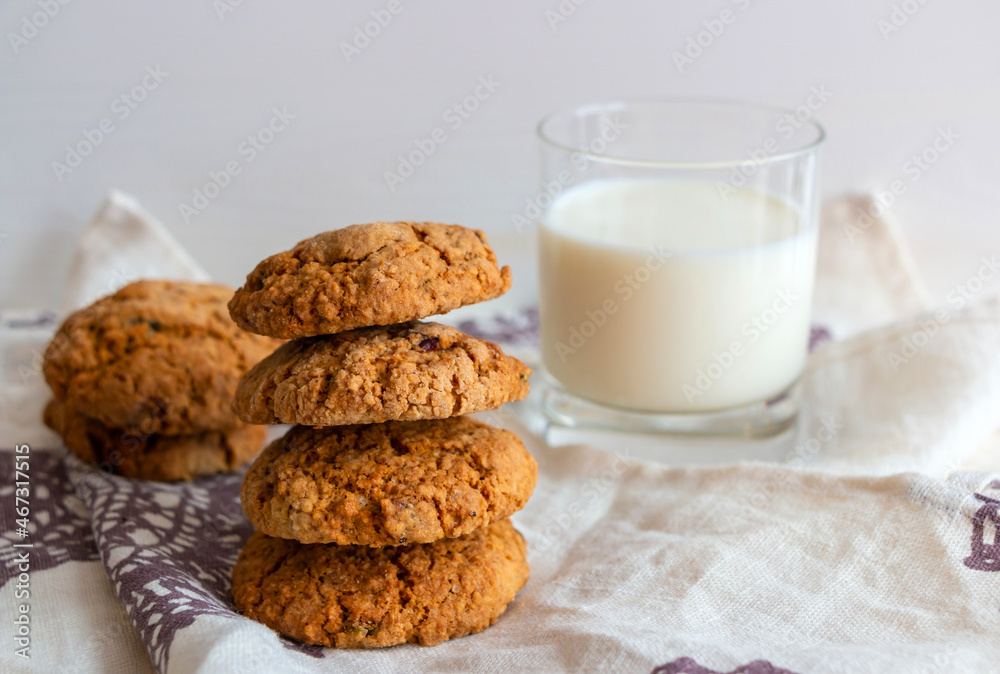 Oatmeal cookies with milk on white background and linen towel with purple snowflakes Oatmeal cookies with milk on white background and linen towel with purple snowflakes