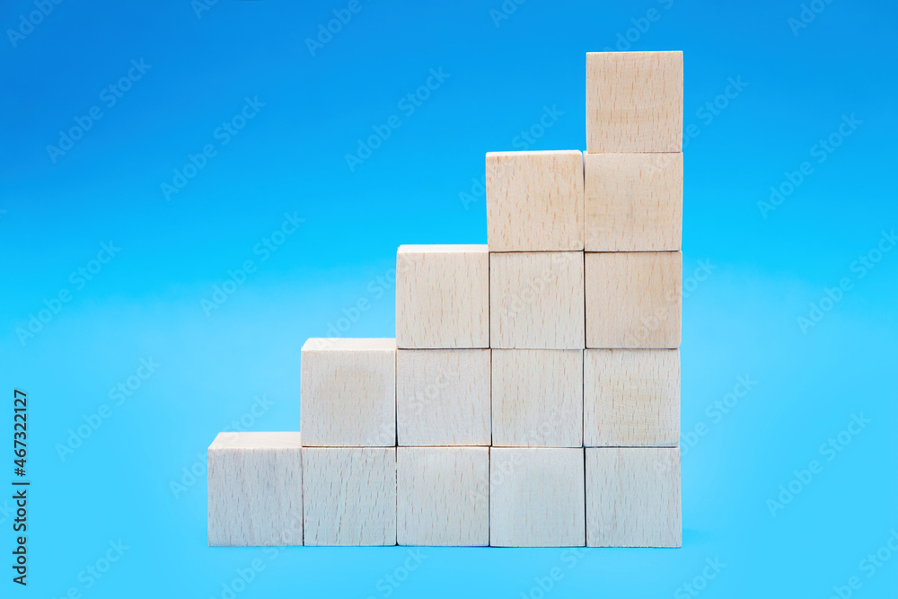Toy wooden blocks stacked into stairs on blue Toy wooden blocks stacked into stairs on blue