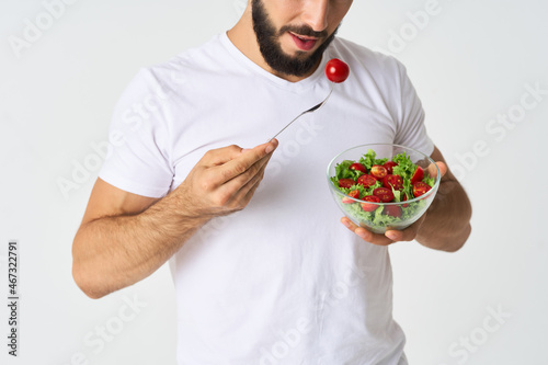 a man in a white t-shirt in a plate with salad a snack healthy food
