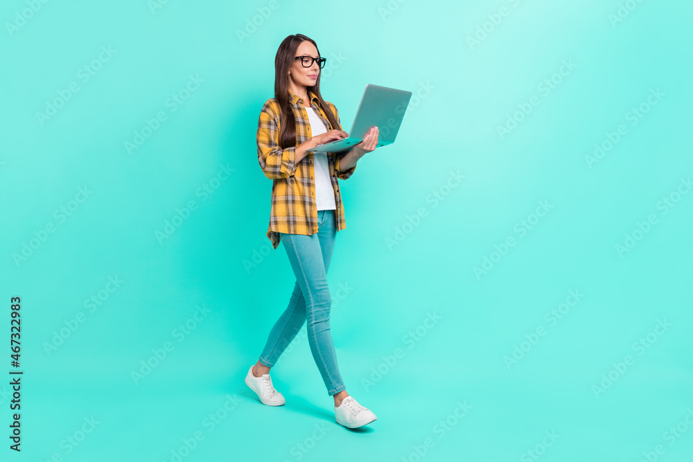 Full size photo of ceo mature brunette lady go write laptop wear eyewear shirt jeans sneakers isolated on teal background Full size photo of ceo mature brunette lady go write laptop wear eyewear shirt jeans sneakers isolated on teal background