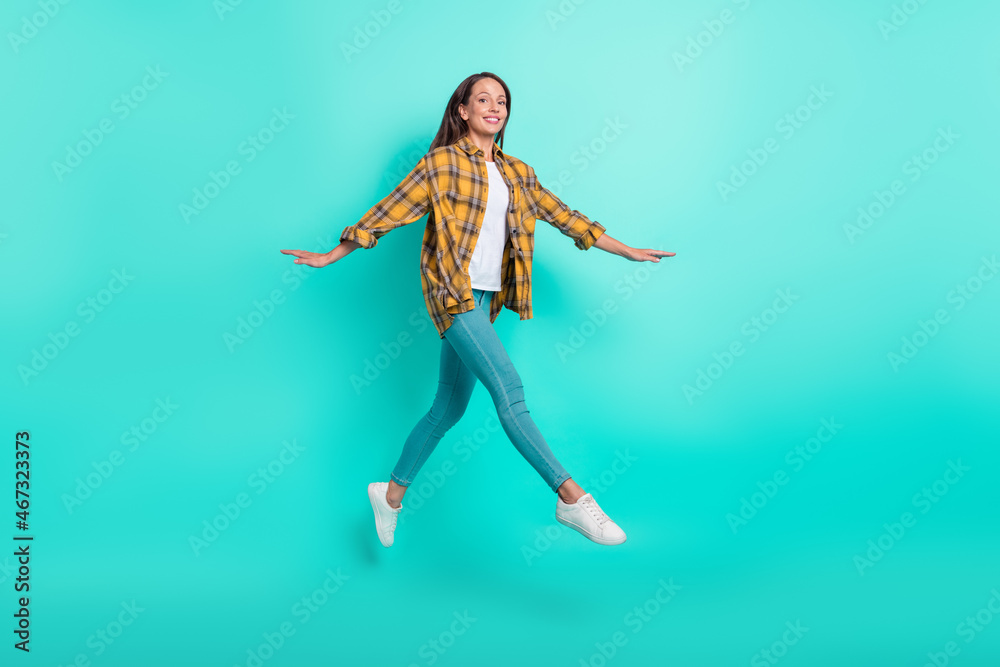 Full size photo of mature joyful brunette lady run wear shirt jeans sneakers isolated on turquoise background