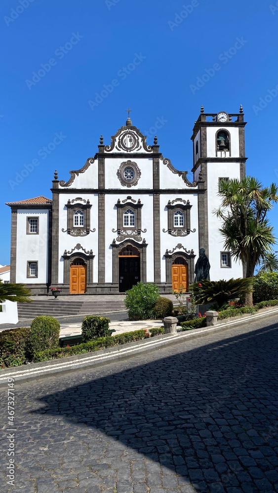 The facade of a white stone building on a street with a steep rise. Tourist Assamadda. Portugal