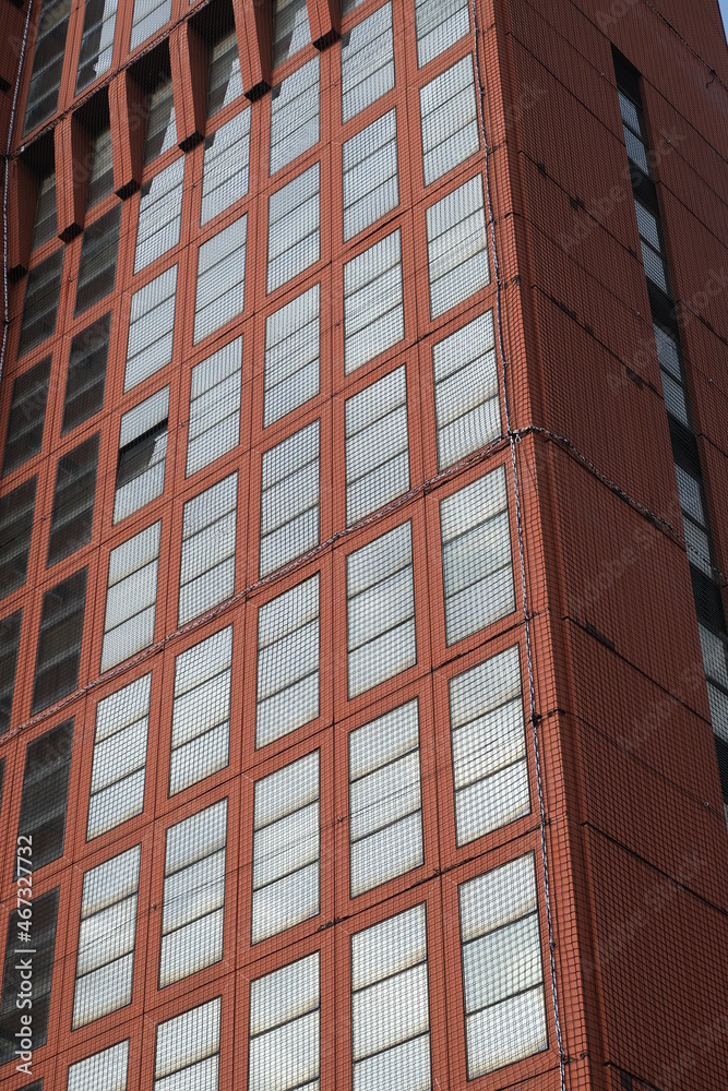 Packaged building. Skyscraper covered with safety net.A modern tower block with glass windows and covered with red tiles that stand out from the walls. Cagliari, Sardinia, Italy. Packaged building. Skyscraper covered with safety net.A modern tower block with glass windows and covered with red tiles that stand out from the walls. Cagliari, Sardinia, Italy.