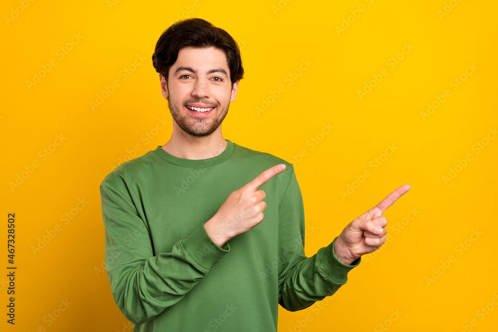 Photo of promoter guy direct finger empty space promo wear green sweater isolated yellow color background Photo of promoter guy direct finger empty space promo wear green sweater isolated yellow color background
