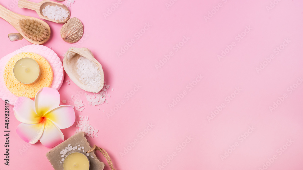 Sea Salt Aroma Candles Face Sponges and Bamboo Face Brush Plumeria Flower and Small Bamboo Scoops with Salt Pink Background Copy space SPA Wellness Banner