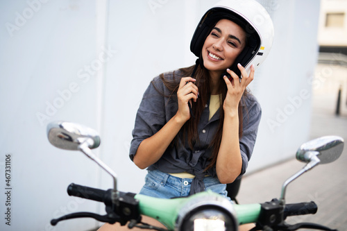 Beautiful woman getting ready for a ride on scooter. Beautiful happy lady having fun outdoors.