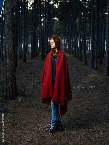 woman in the woods covered herself with a red blanket walk fresh air