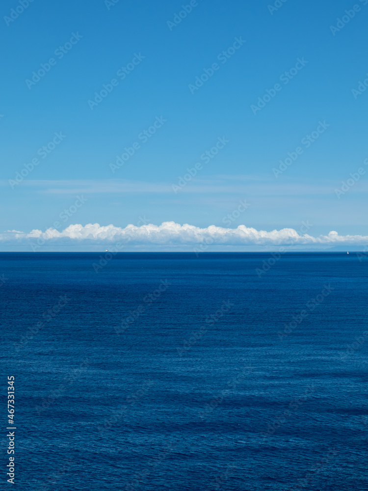 Blue Ionian sea and skyscape vertical view in Greece. Bright day with scenic white clouds over rippled deep blue water surface